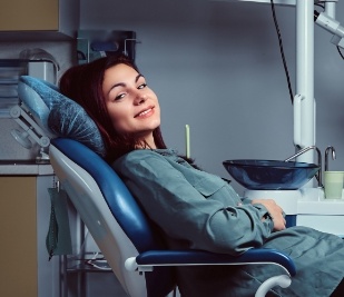 Woman in green jacket smiling in dental chair