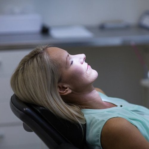 Woman resting in dental examination chair after taking oral conscious sedation