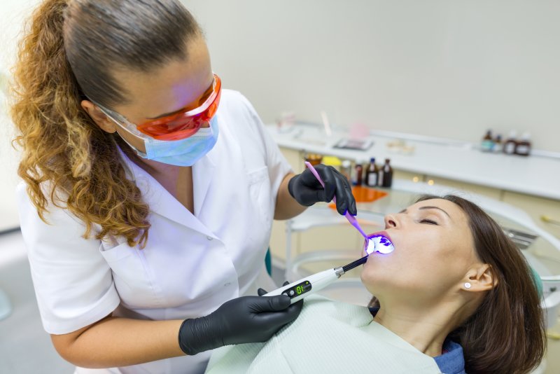 A dentist treating a woman who is under dental sedation